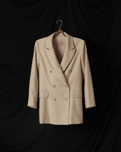 Cream double-breasted blazer on a brass hanger