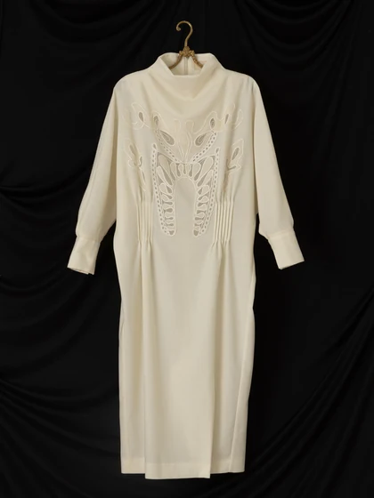 Ivory dress with cord embroidery on a brass hanger