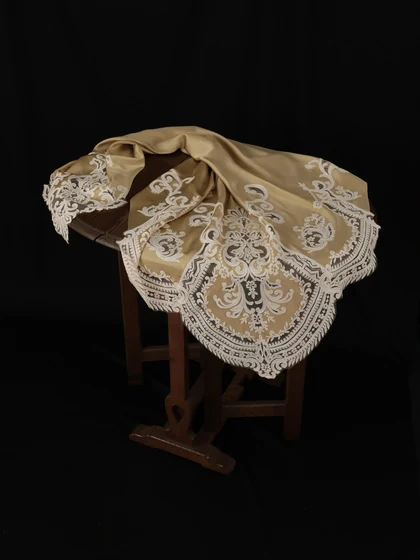 Champagne satin cloth with lace embroidery draped over a wooden table